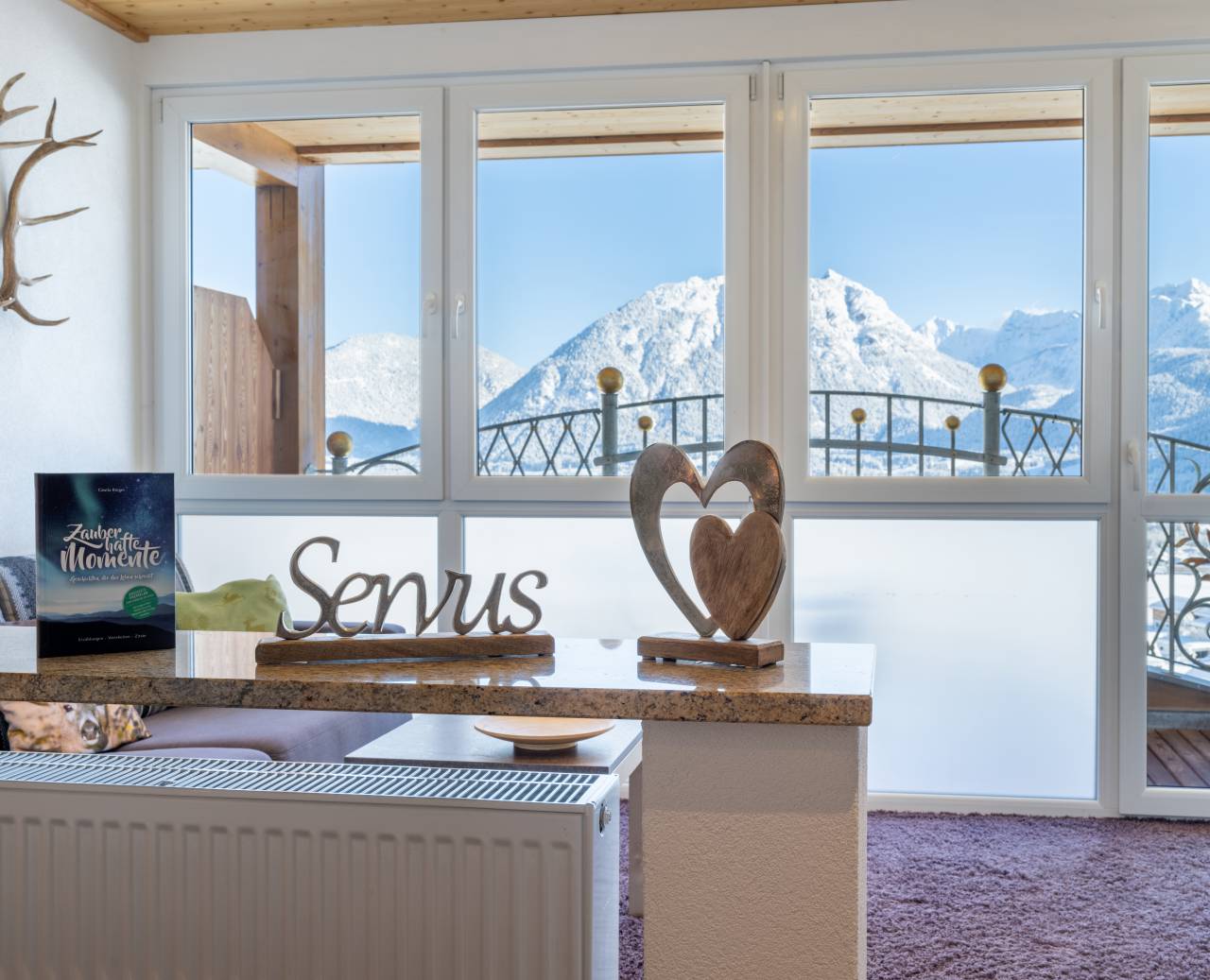 Panoramisch uitzicht vanuit de kamer op besneeuwde Alpen met Servus-decoratie