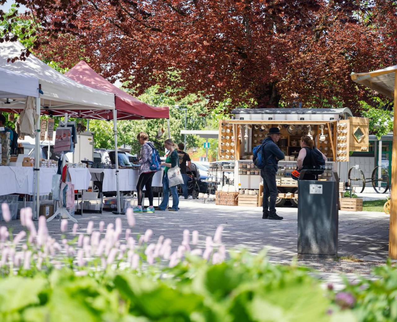 Market with stalls, visitors and flowers in the foreground