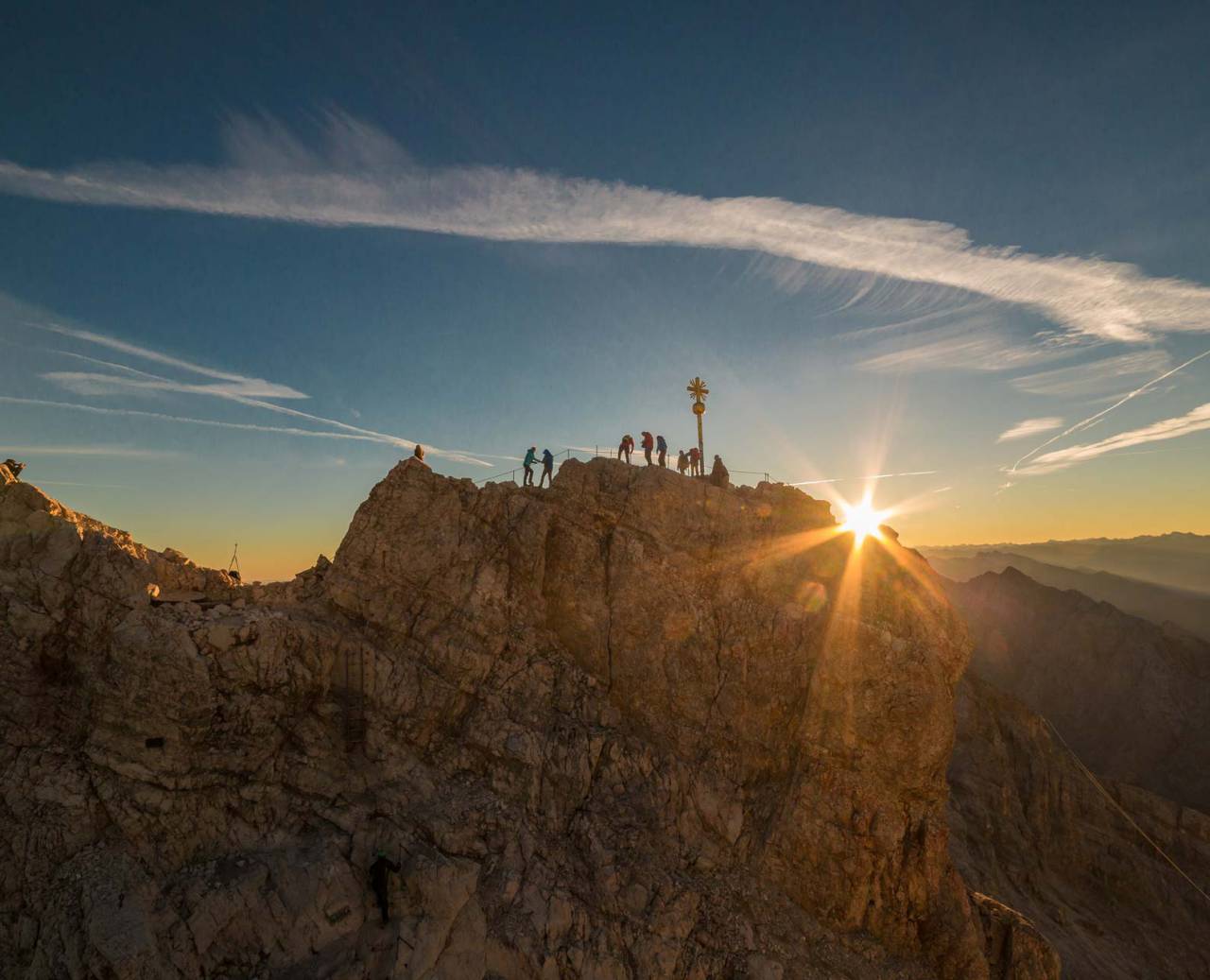 Sunrise at Zugspitze with climbers near the summit cross