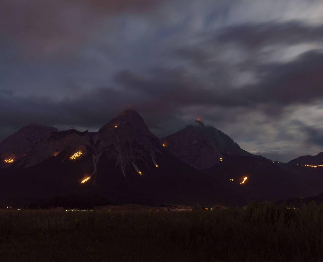 Glowing solstice fires on mountain peaks at night