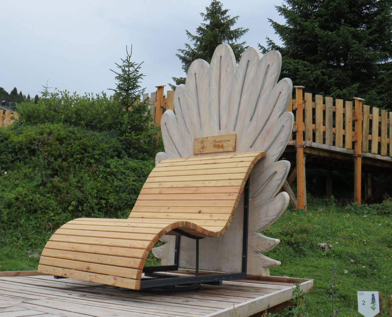 Wooden lounger with rooster comb design on an alpine meadow