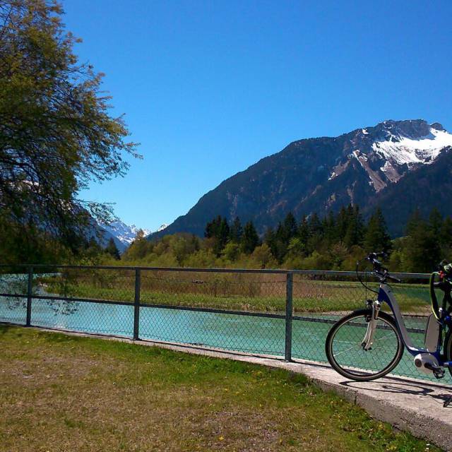 Bicycle by riverside with view of snow-capped mountains