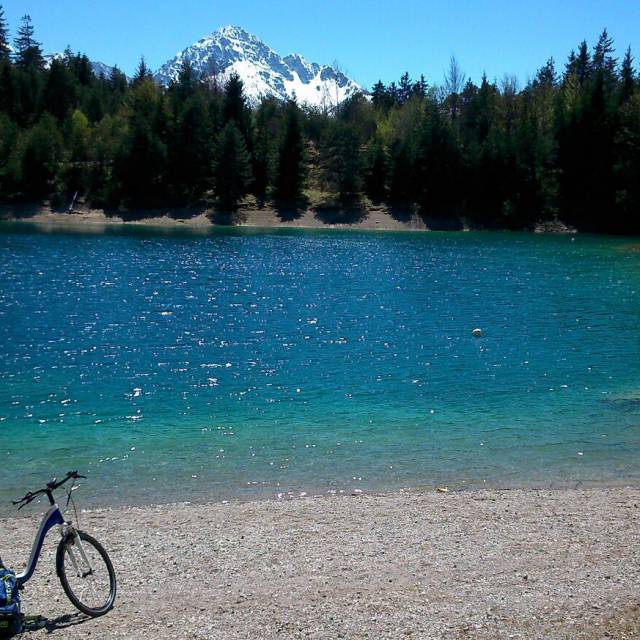 E-bike in front of mountain lake in forest with snowy mountains