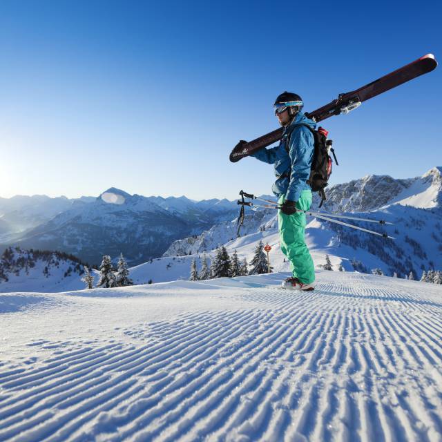 Mann auf einer frisch präparierten Skipiste bei strahlendem Sonnenschein