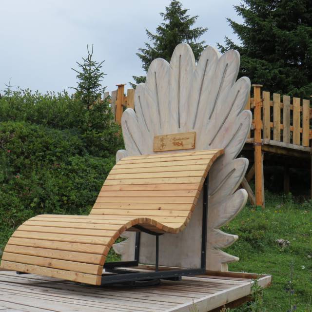 Wooden lounger with rooster comb design on an alpine meadow
