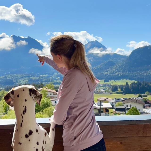 Frau mit ihrem Hund steht am Balkon der Panoramasuite und genießt den Ausblick