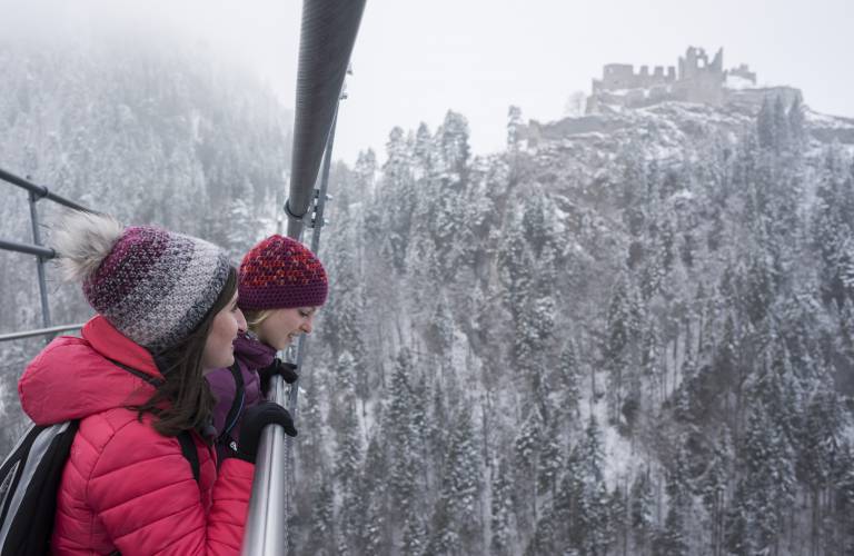 Frauen wandern die Hängebrücke Highline179 in der Natur in den verschneiten Bergen und Burgen