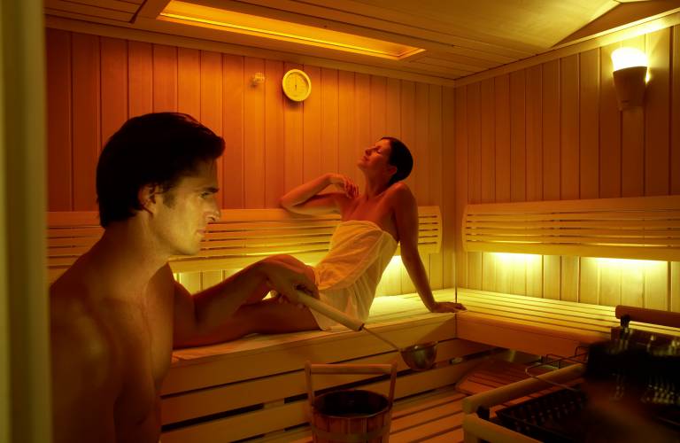 Man en vrouw zweten en ontspannen in een kleine sauna tijdens een opgieting