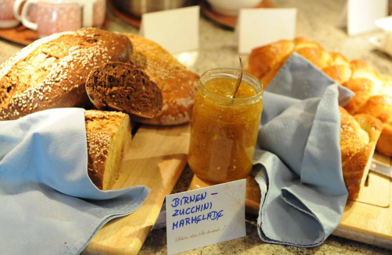 Vers wit- en zwartbrood op snijplanken met peren-courgettejam in een potje