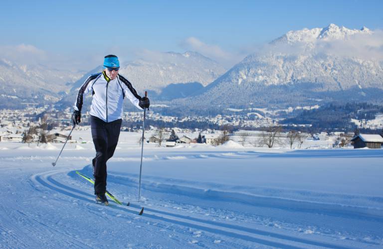 Ein Langläufer zieht seine Tour durch die verschneite Winterlandschaft