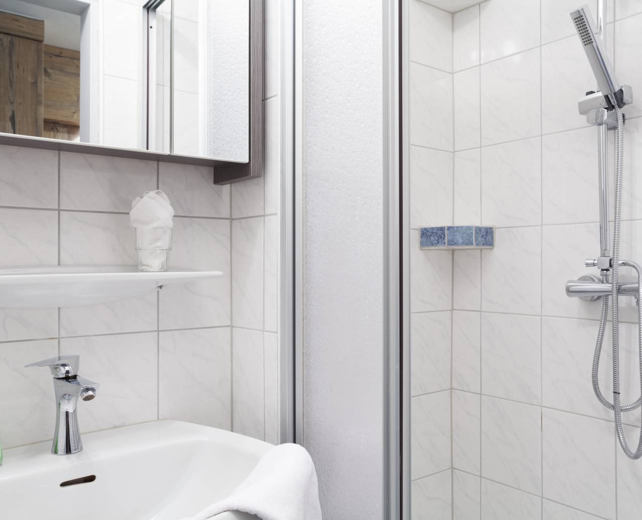 White tiled bathroom with shower, sink and mirror box