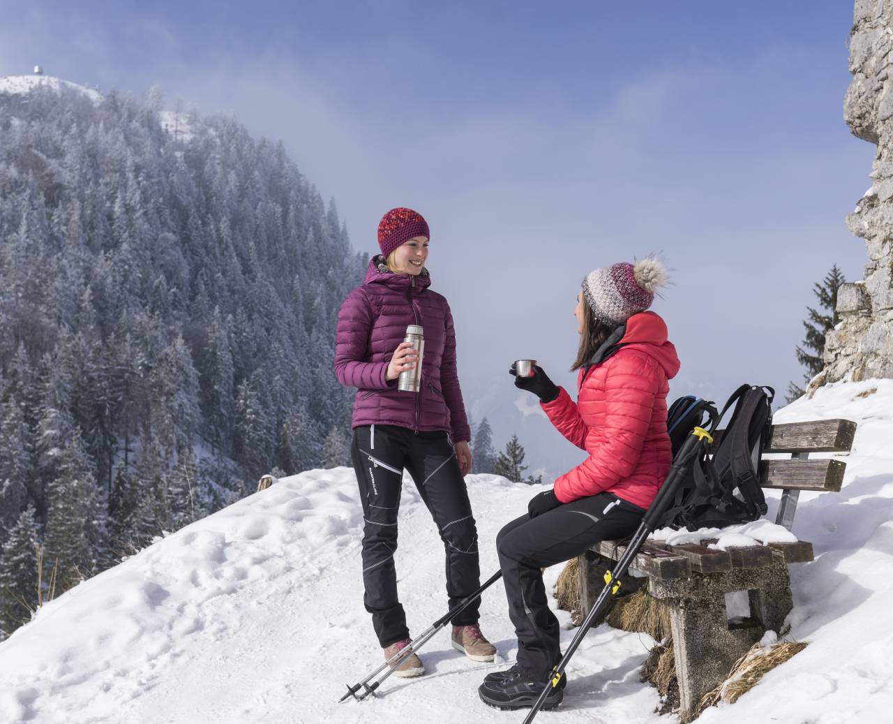 Paar bei einer Teepause während eines Winterspaziergangs mit Wanderstöcken