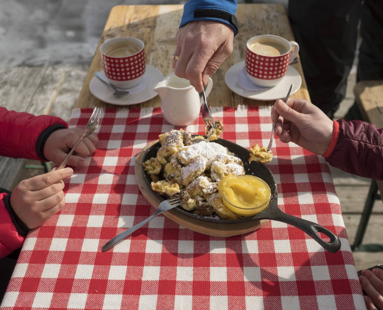 Frischer Kaiserschmarrn in der Pfanne mit Staubzucker, Apfelmus und Kaffee mit Milch