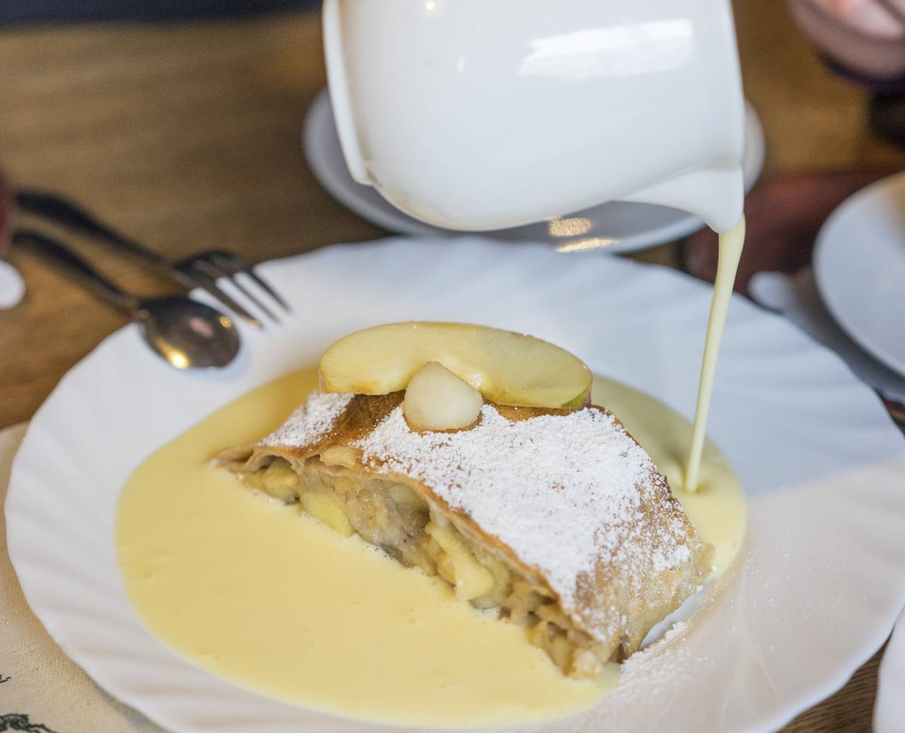 Fresh apple strudel with powdered sugar and vanilla sauce