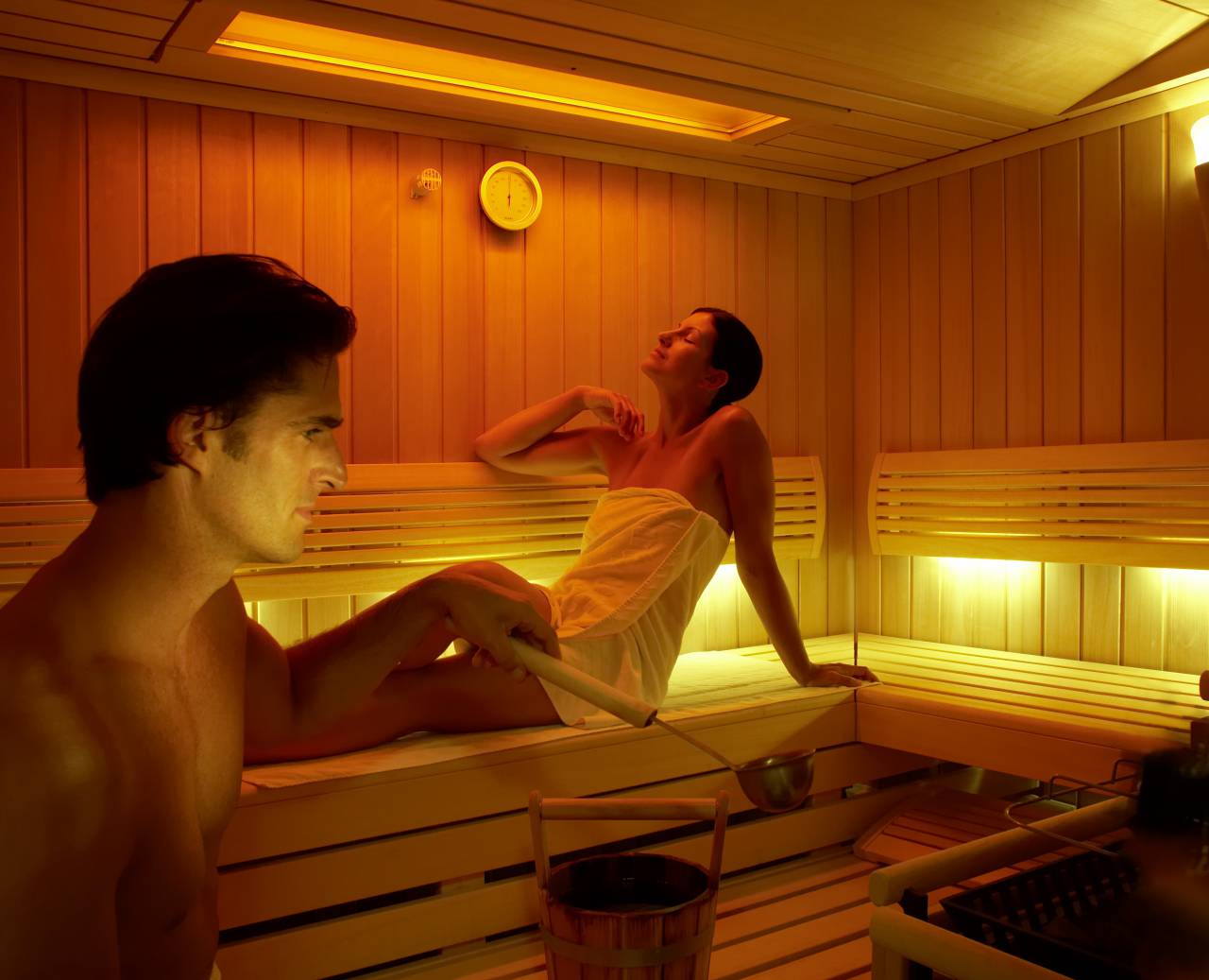 Mann und Frau schwitzen und entspannen in einer kleinen Sauna bei einem Aufguss