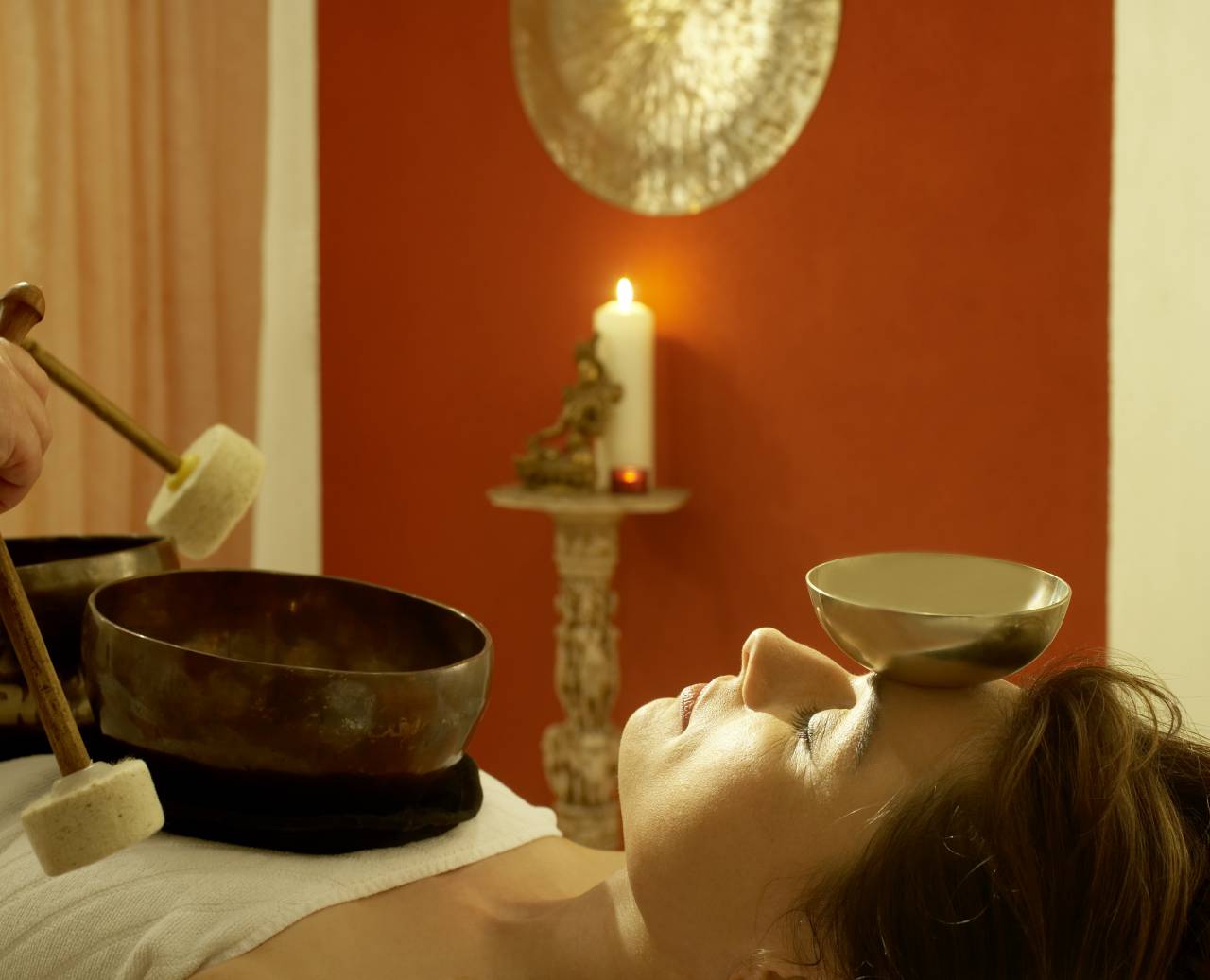 Woman relaxing in candlelight with a singing bowl mass