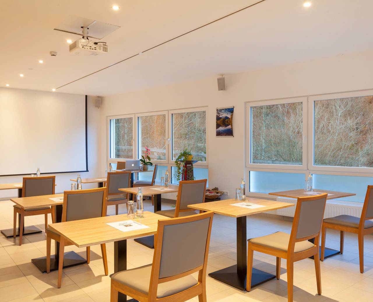 Plain seminar room with seating, drinks and large projector screen 