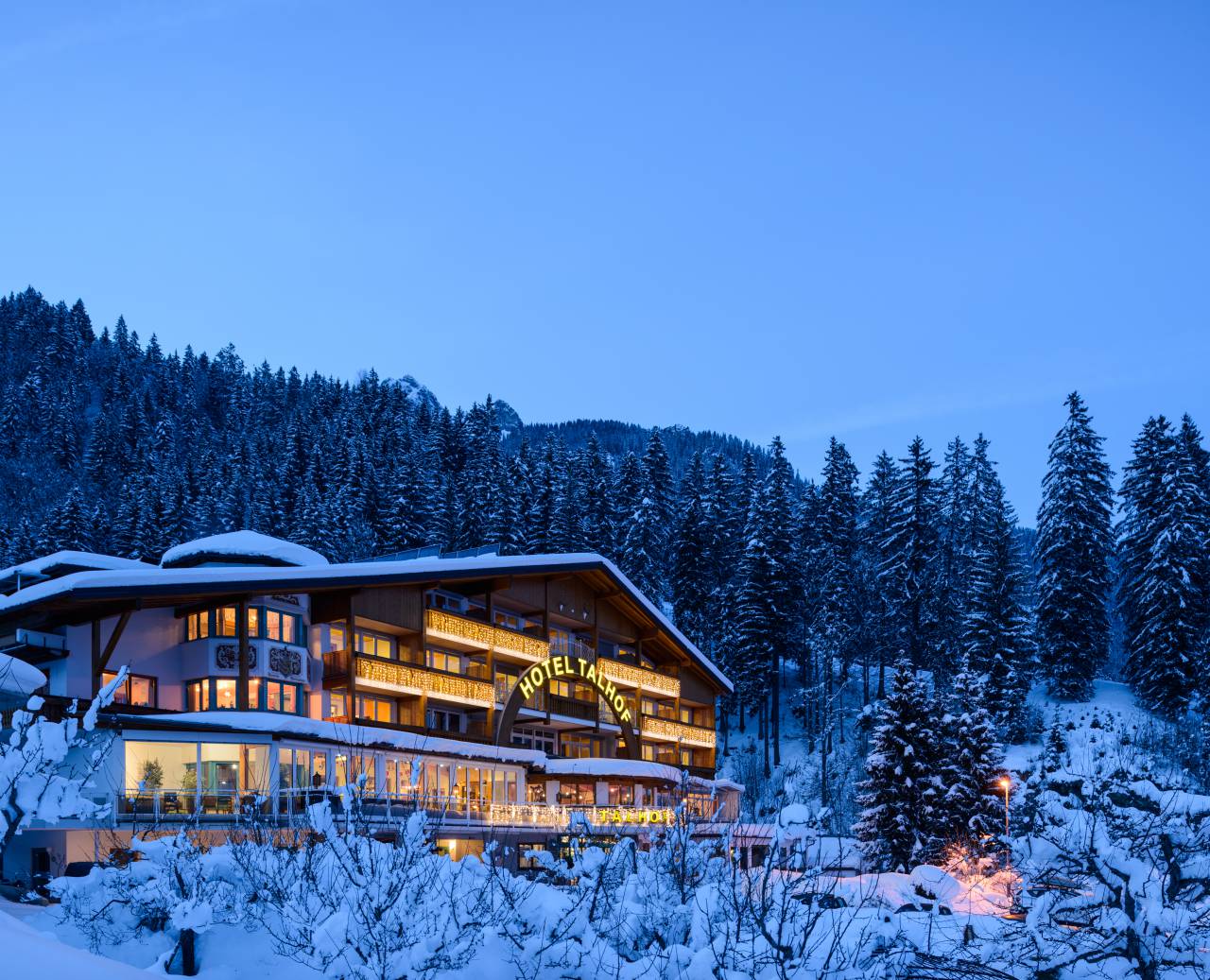 Beschneites Panoramahotel Talhof im Wald in den Bergen bei Abenddämmerung