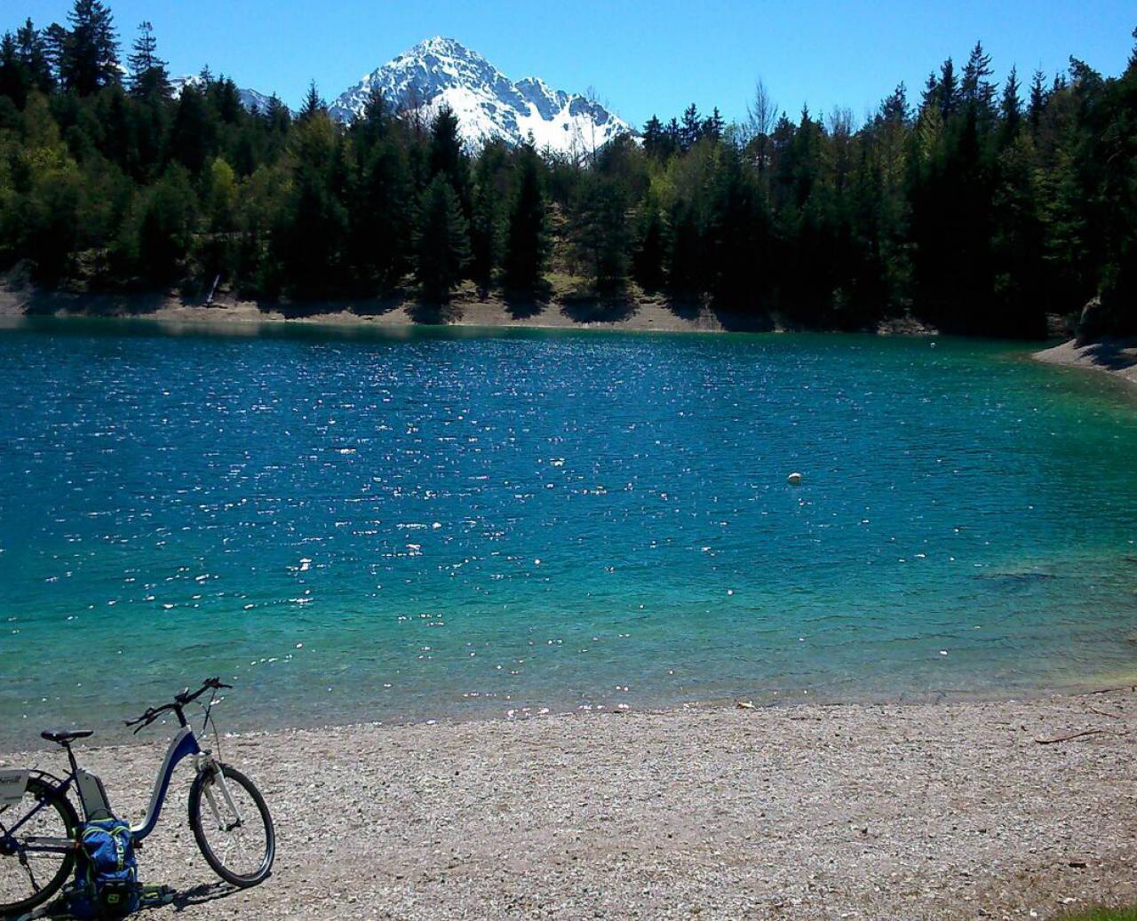 E-bike in front of mountain lake in forest with snowy mountains