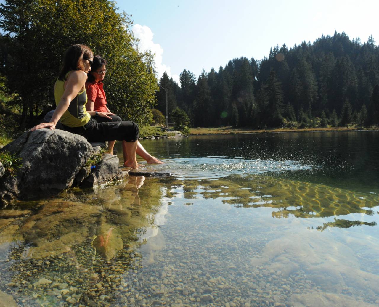 Women dangling their feet in the water of a lake in summer