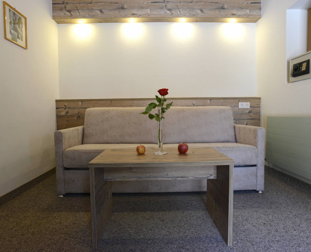 Hotel room with grey couch, table, room safe and spotlights