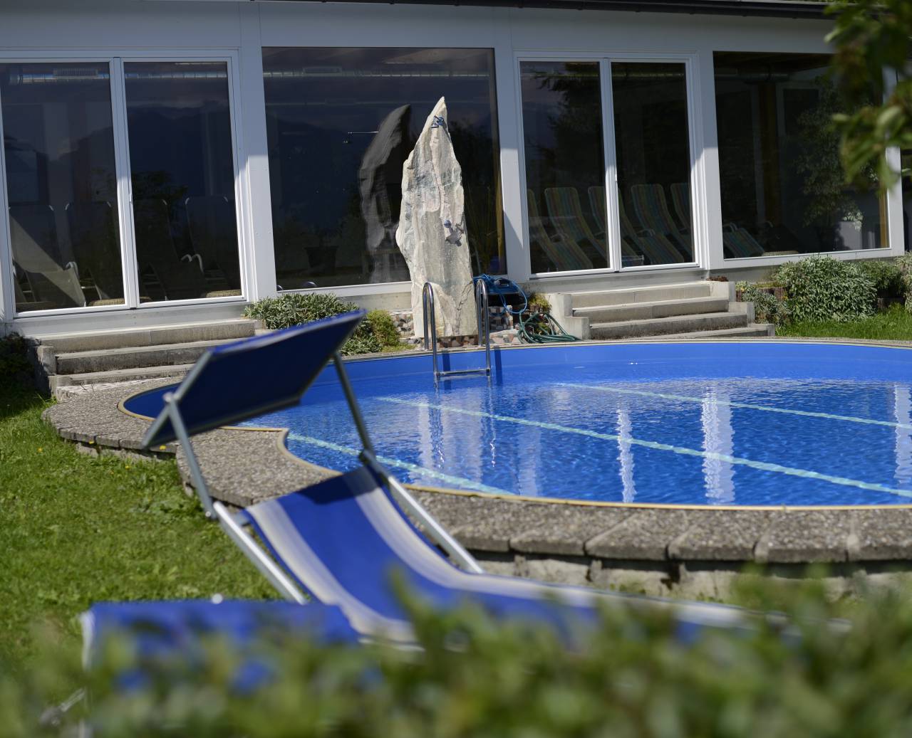 Outdoor pool in the garden with sun loungers in summer