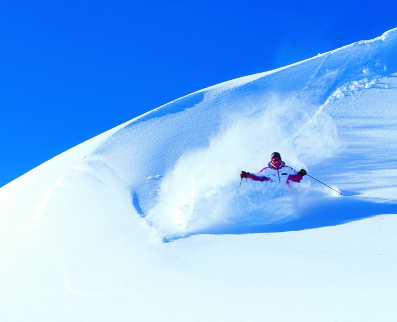 Skifahrer abseits der Skipiste im frischen Neuschnee bei wolkenlosem Himmel