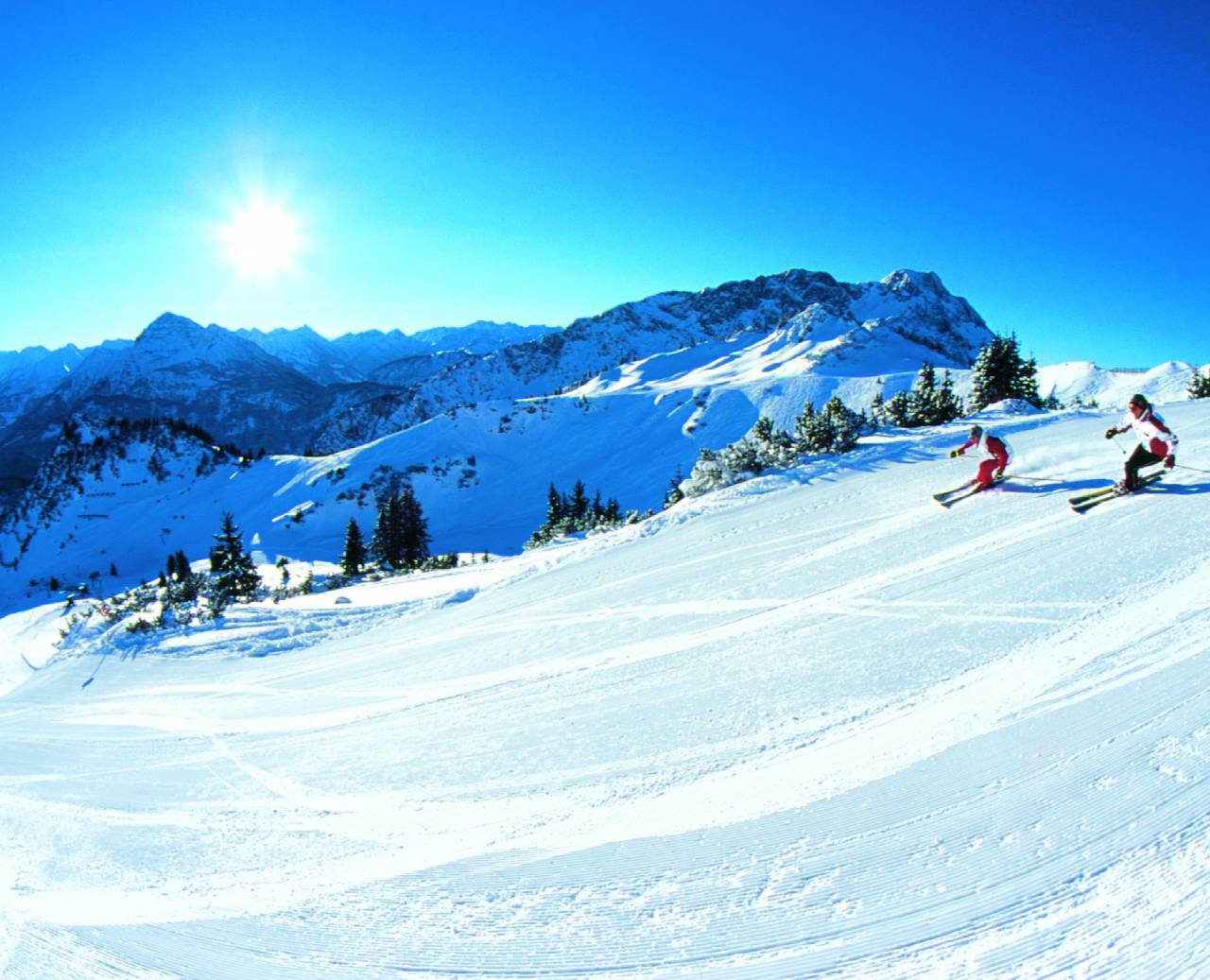 Skiers on a freshly groomed ski slope in the morning sunshine