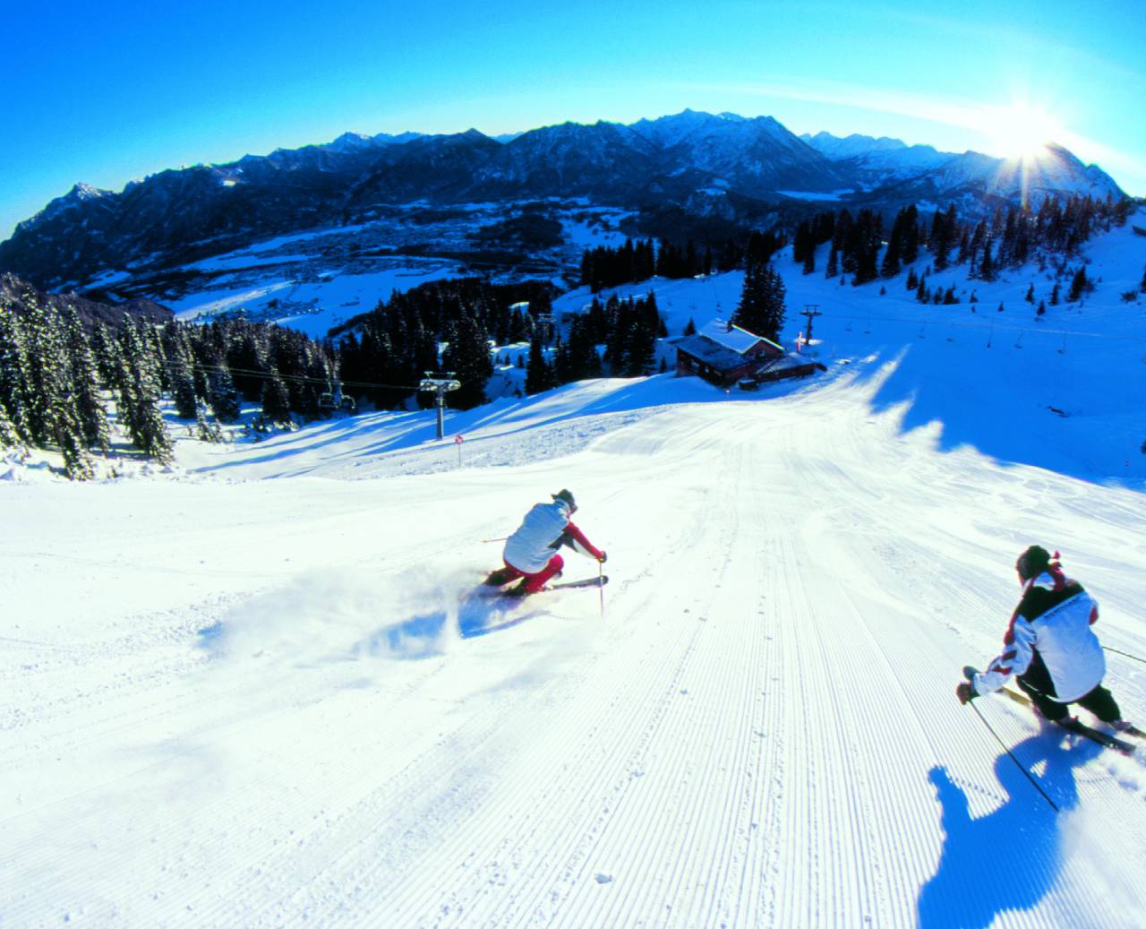 Skifahrer auf einer frisch präparierten Skipiste am Morgen bei Sonnenschein