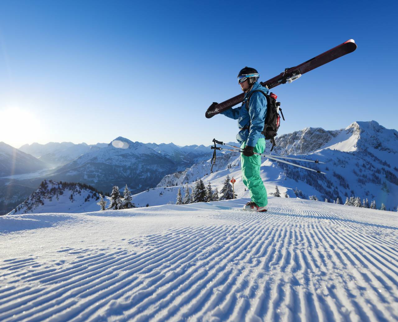 Mann auf einer frisch präparierten Skipiste bei strahlendem Sonnenschein