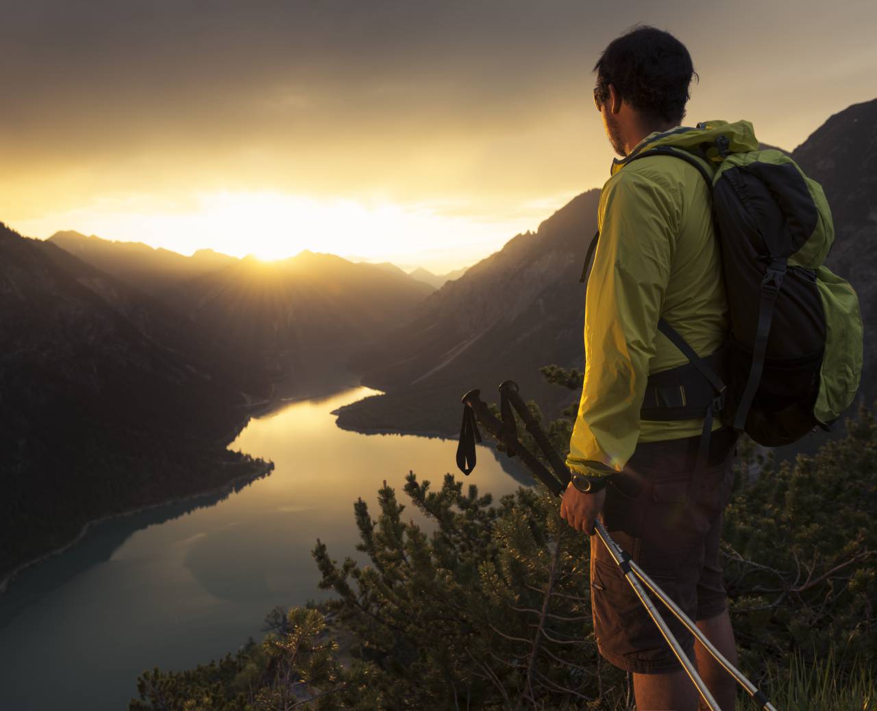 Mann beim Wandern mit Blick auf einen See bei Sonnenuntergang