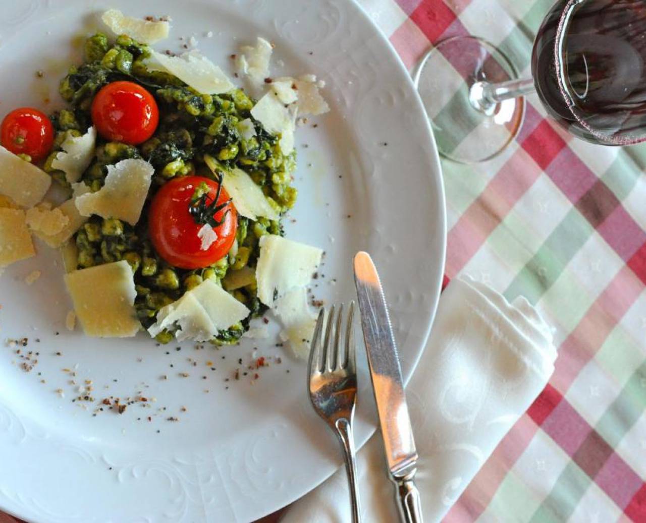 Dekorativ angerichtete Speise mit frischen Tomaten, Parmesan und ein Glas Rotwein