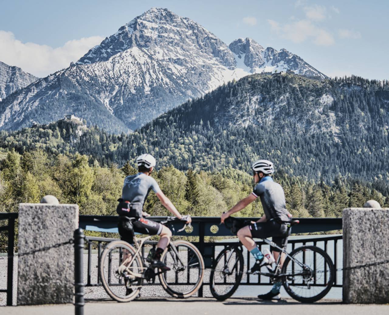 Radfahrer bei einer Pause mit Blick auf die verschneiten Berge