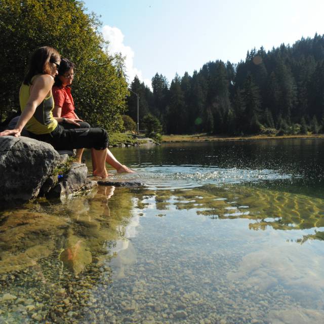 Women dangling their feet in the water of a lake in summer