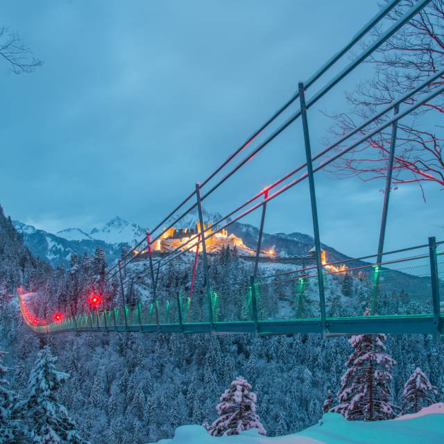 Illuminated suspension bridge highline179 with illuminated Ehrenberg castle ruins in winter