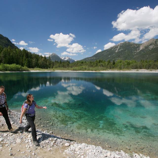 Couple walking with hiking backpacks on the lakeshore